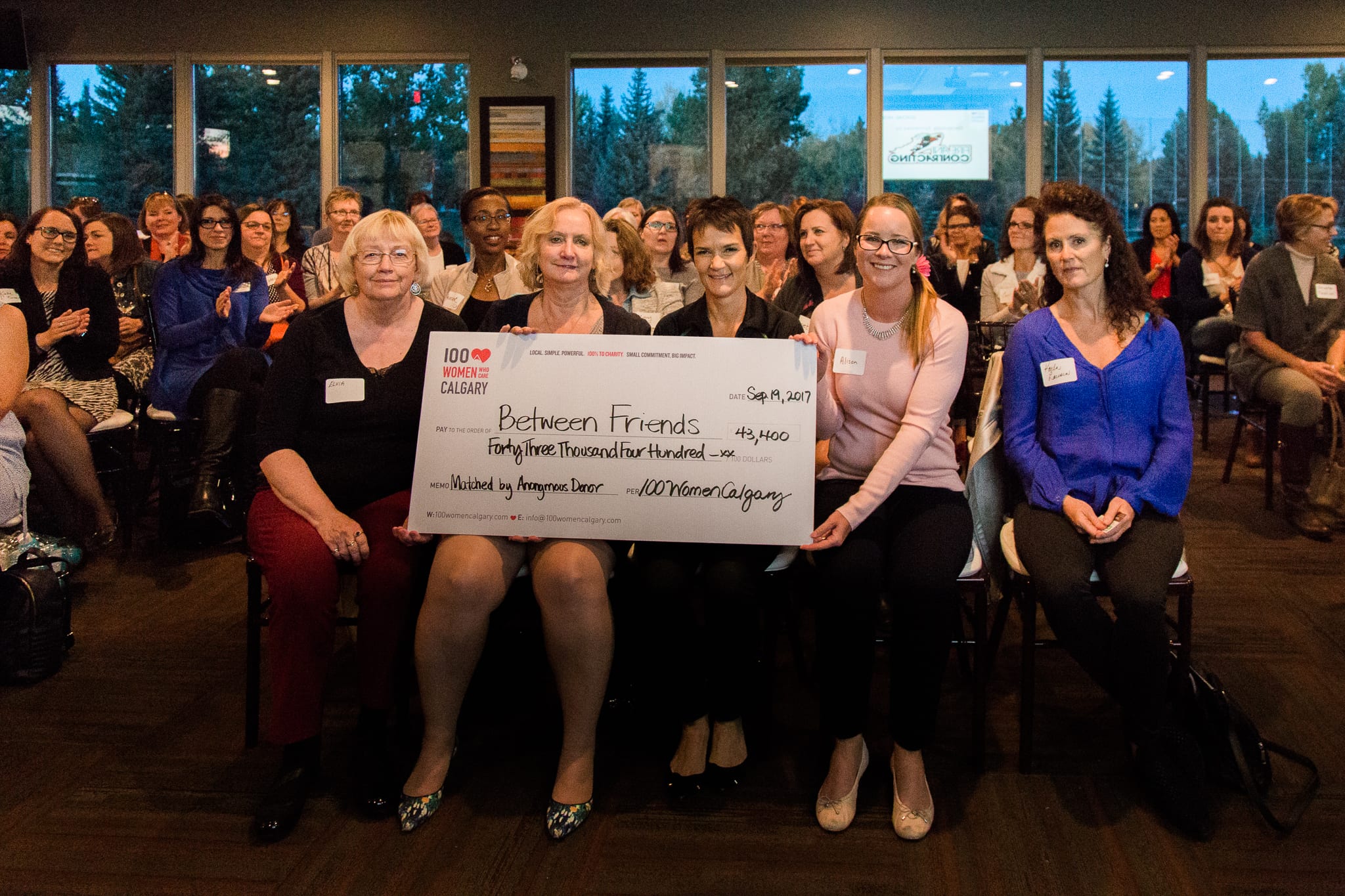 100 women with cheque for Between Friends charity